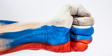 Un avant-bras au poing serré maquillé aux couleurs du drapeau russe.